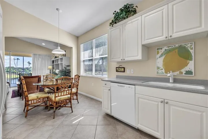 Kitchen with white cabinetry, white dishwasher, hanging light fixtures, lofted ceiling, and light tile patterned flooring