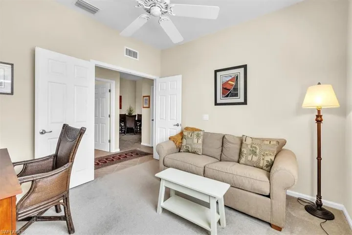 Tiled living room featuring carpet flooring, ceiling fan, and a desk