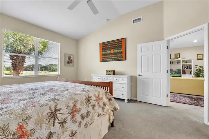 Bedroom featuring light colored carpet, vaulted ceiling, and ceiling fan