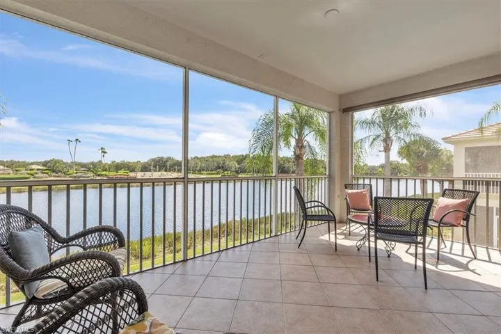 Sunroom / solarium featuring tile patterned floors and a water view