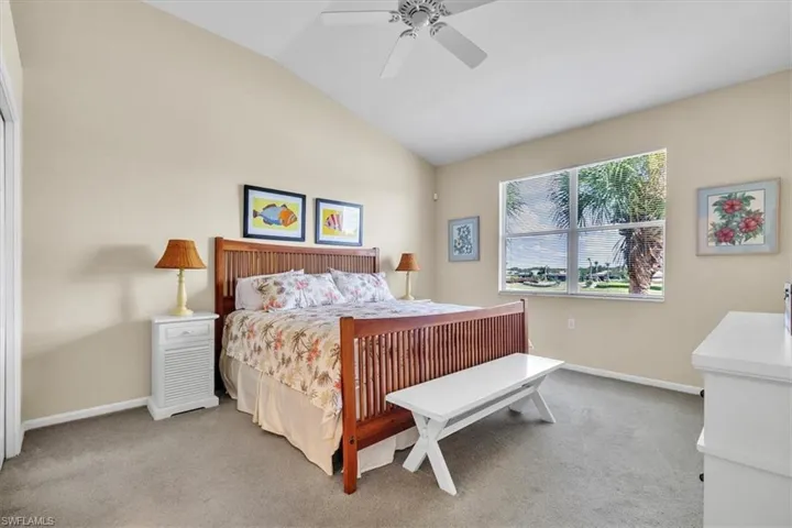 Bedroom with light colored carpet, vaulted ceiling, and a ceiling fan