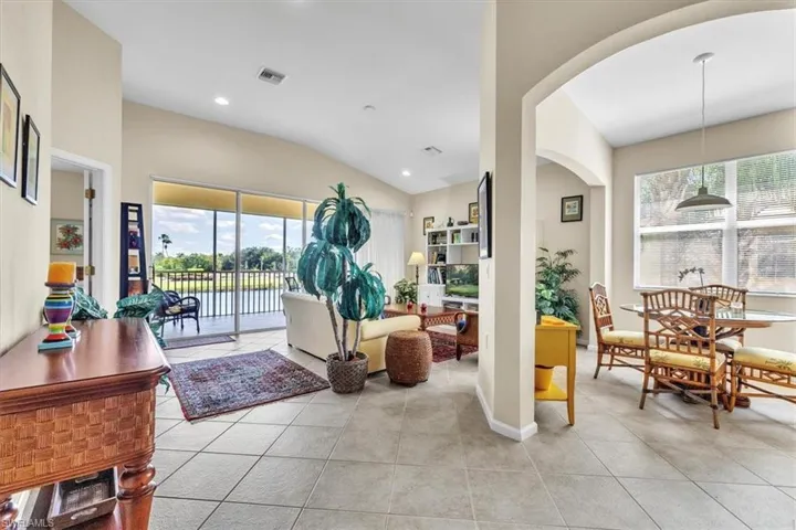 Living room with lofted ceiling, light tile patterned floors, recessed lighting, and arched walkways