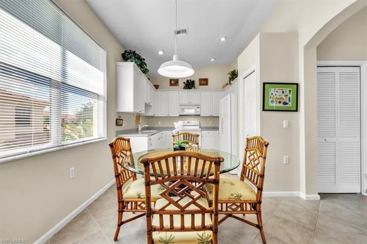 Dining area with arched walkways, recessed lighting, and light tile patterned floors