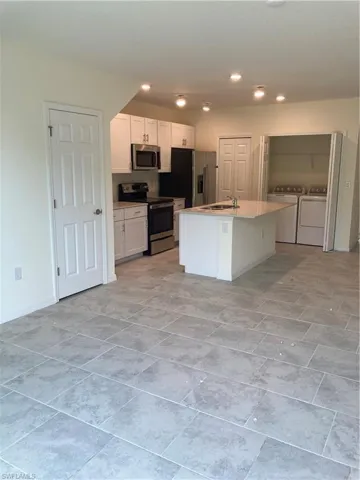 Kitchen with range, separate washer and dryer, white cabinetry, refrigerator, and recessed lighting