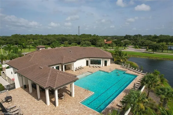 Community pool with fence, a patio, a water view, and view of scattered trees