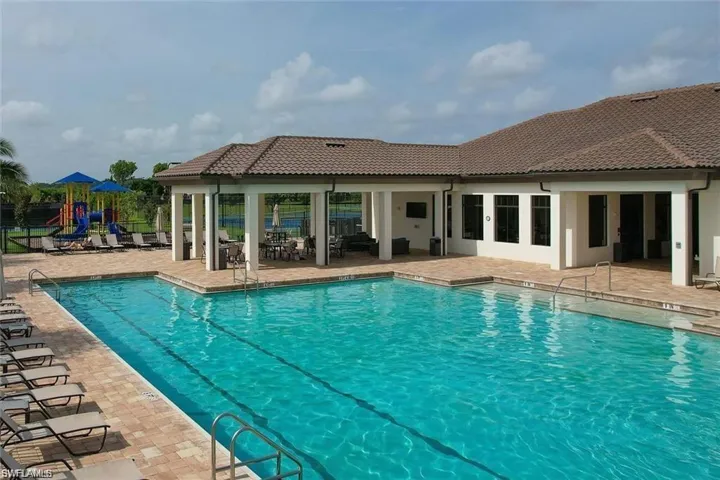 Community pool with a patio, a playground, and fence