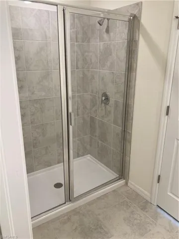 Bathroom with a shower stall and baseboards