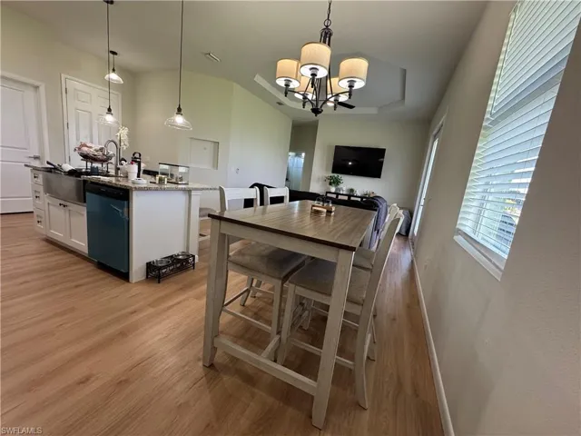 Dining area with light wood-type flooring, a chandelier, and baseboards