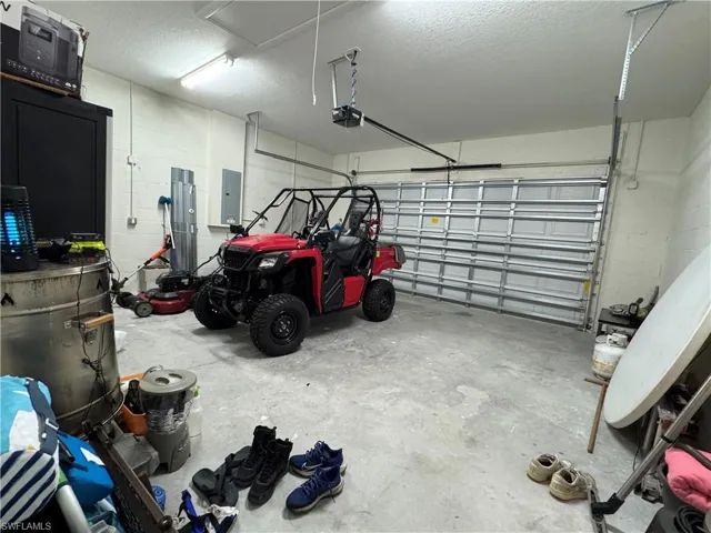 Garage featuring a garage door opener, concrete block wall, and electric panel
