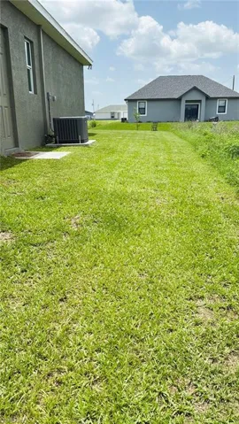 View of grassy yard featuring central air condition unit
