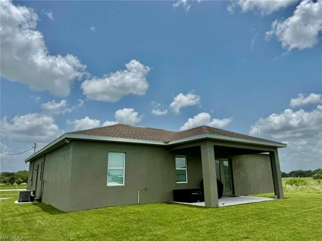 Back of house with stucco siding, a patio, a yard, and cooling unit