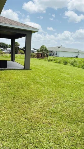View of grassy yard featuring a patio area