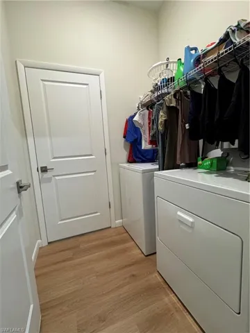 Laundry room with independent washer and dryer and light wood-style floors