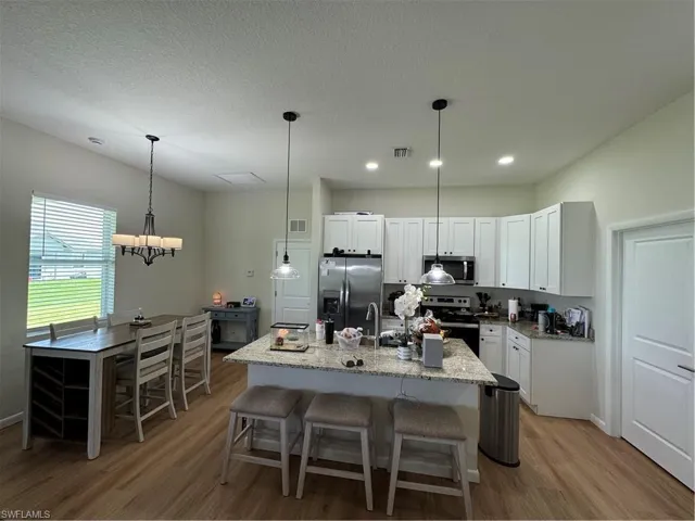 Bedroom with wood finished floors, a raised ceiling, baseboards, ensuite bathroom, and a ceiling fan