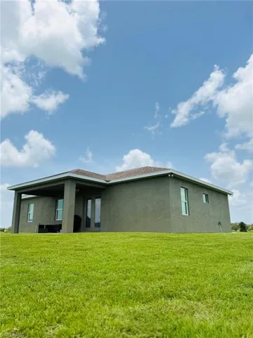 Back of house with stucco siding and a yard