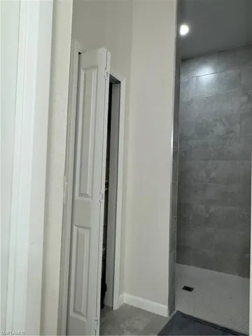 Bathroom with tiled shower and baseboards