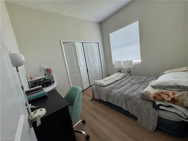 Bedroom with wood finished floors, a closet, and an office area