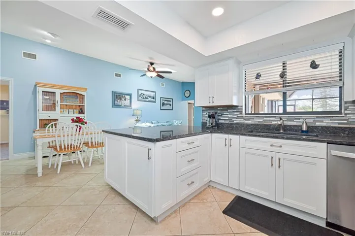 Kitchen with a sink, dishwasher, a peninsula, and decorative backsplash