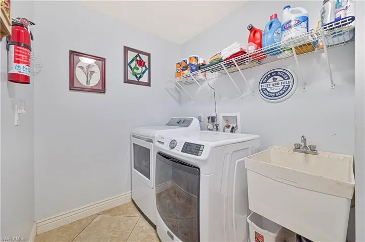 Laundry area with washer and clothes dryer, baseboards, and light tile patterned flooring