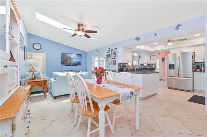 Dining room with ceiling fan, light tile patterned floors, and vaulted ceiling