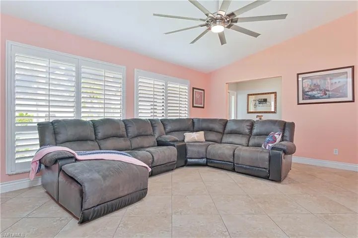 Living area with ceiling fan, plenty of natural light, vaulted ceiling, and baseboards