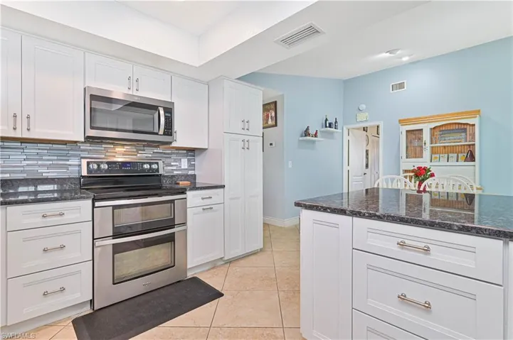 Kitchen with appliances with stainless steel finishes, decorative backsplash, white cabinets, and light tile patterned floors