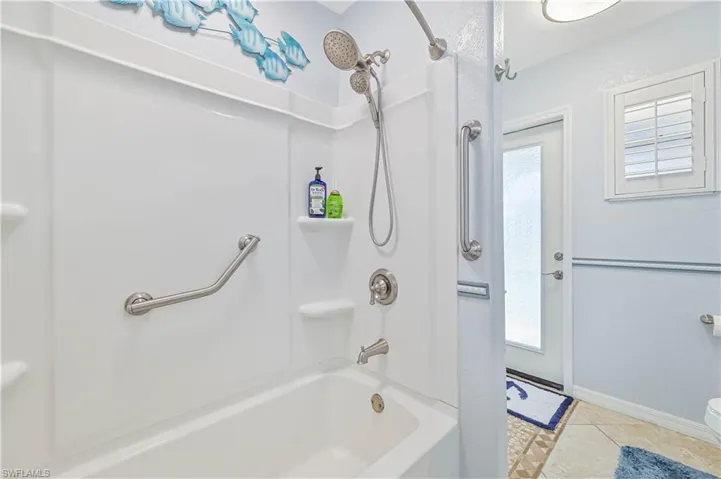 Full bathroom with shower / bathtub combination, healthy amount of natural light, baseboards, and tile patterned floors