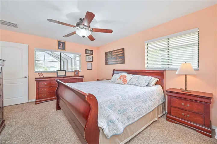 Bedroom featuring multiple windows, light colored carpet, ceiling fan, and baseboards