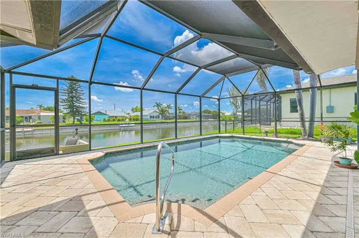 Outdoor pool with a water view, a patio, and glass enclosure