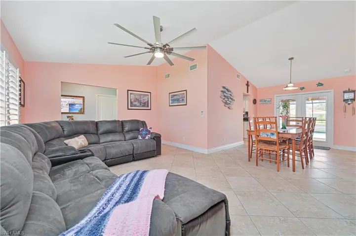 Living room featuring a ceiling fan, light tile patterned flooring, baseboards, french doors, and high vaulted ceiling