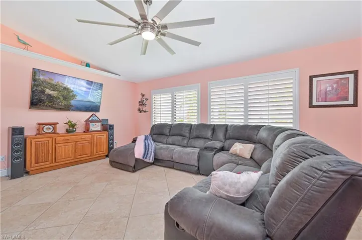 Living room featuring lofted ceiling, ceiling fan, and light tile patterned floors