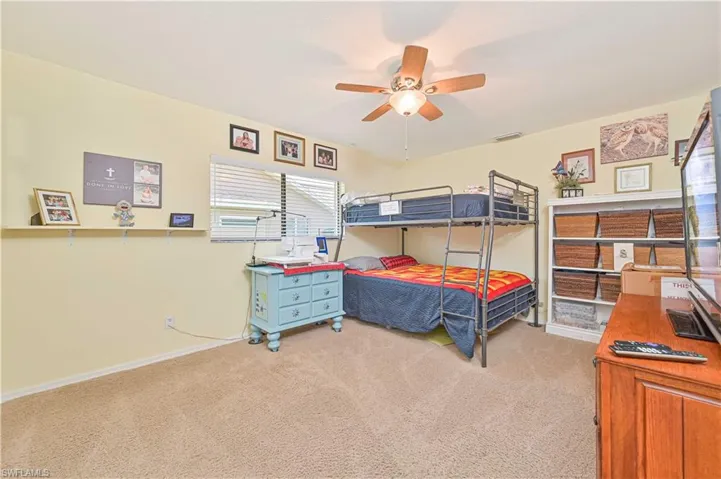 Bedroom featuring light colored carpet, baseboards, and ceiling fan