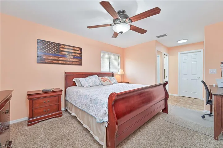 Bedroom featuring light carpet, ceiling fan, and baseboards