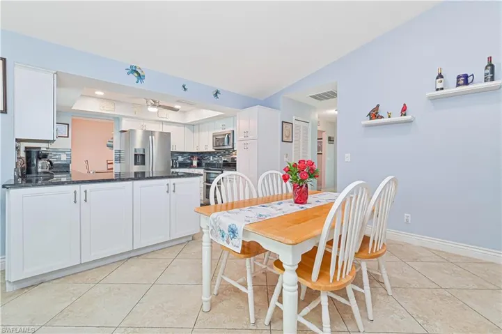 Dining area featuring light tile patterned floors, a raised ceiling, baseboards, and a ceiling fan
