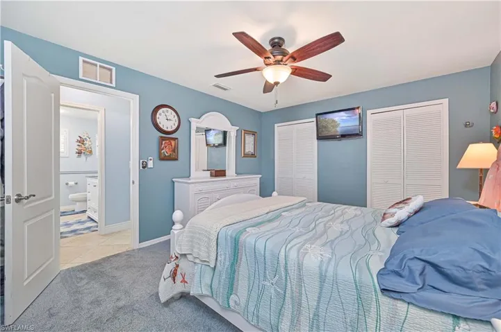 Bedroom featuring multiple closets, baseboards, light colored carpet, a ceiling fan, and light tile patterned floors