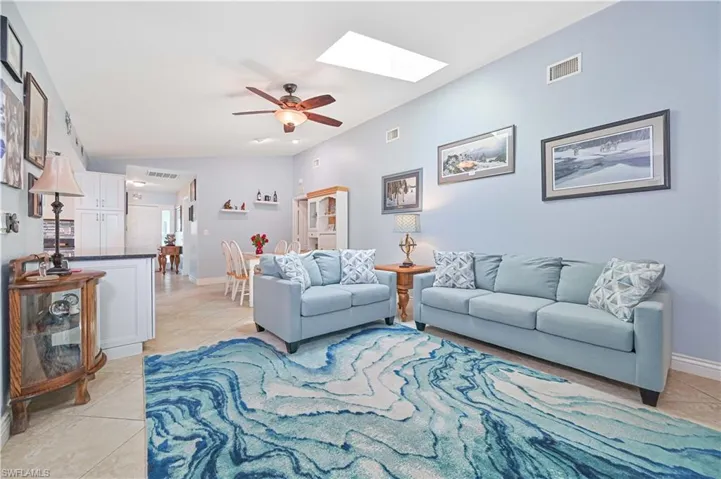 Living area with light tile patterned floors, a skylight, ceiling fan, and baseboards