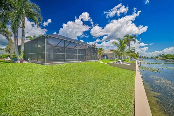 View of grassy yard featuring a water view and glass enclosure