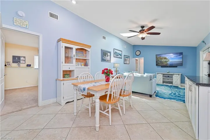 Dining area featuring a ceiling fan, light tile patterned flooring, lofted ceiling, and baseboards