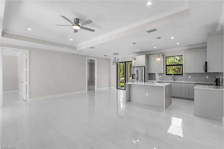 Kitchen featuring crown molding, decorative backsplash, gray cabinets, recessed lighting, and open floor plan