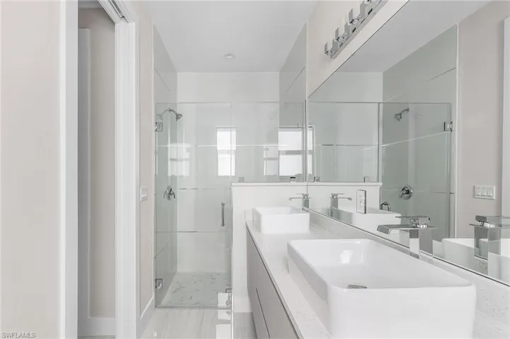 Full bath with a stall shower, double vanity, and light tile patterned floors