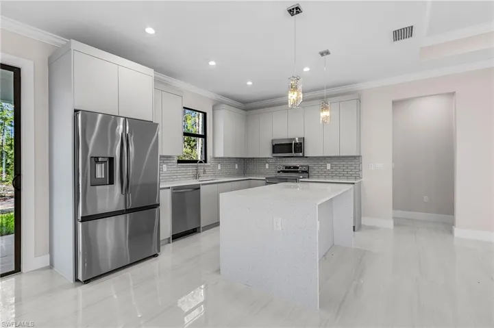 Kitchen with stainless steel appliances, backsplash, ornamental molding, a center island, and pendant lighting