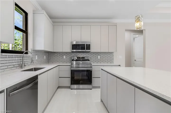 Kitchen featuring appliances with stainless steel finishes, tasteful backsplash, modern cabinets, and ornamental molding