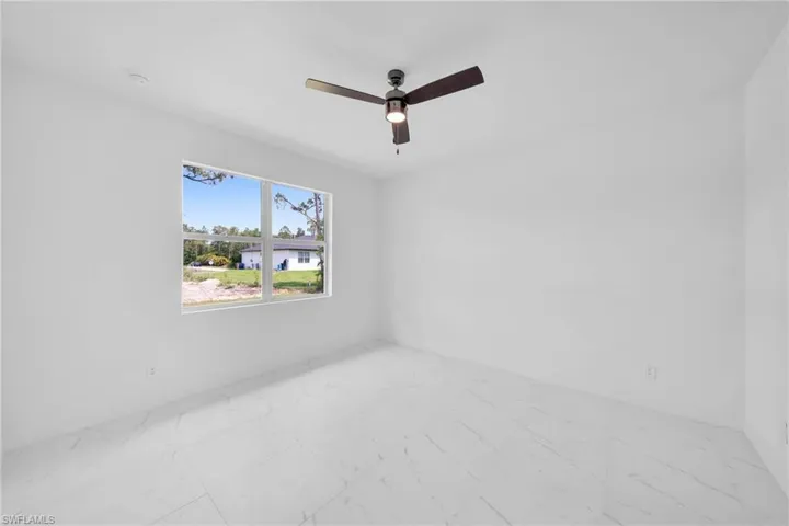 Tiled spare room featuring ceiling fan
