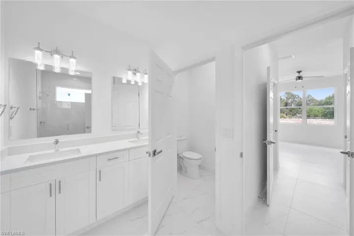 Bathroom featuring ceiling fan, toilet, tile floors, and double vanity