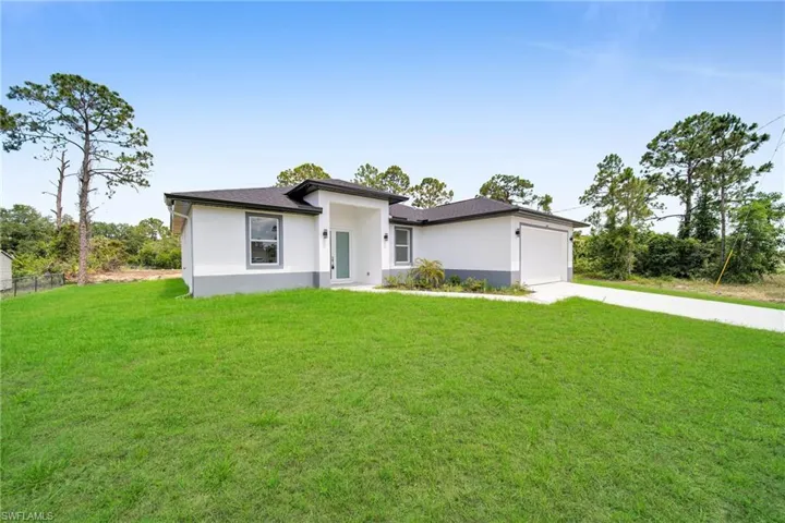 View of front of property with a garage and a front lawn