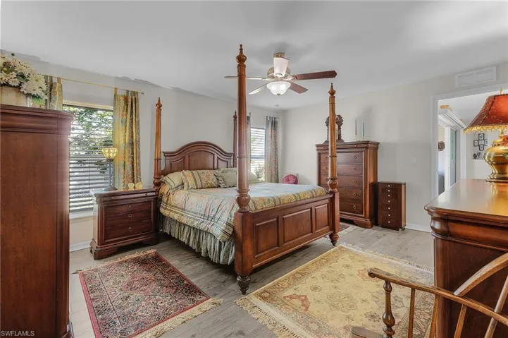 Bedroom with light hardwood / wood-style floors, multiple windows, and ceiling fan