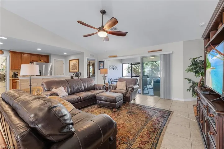 Tiled living room with ceiling fan and lofted ceiling