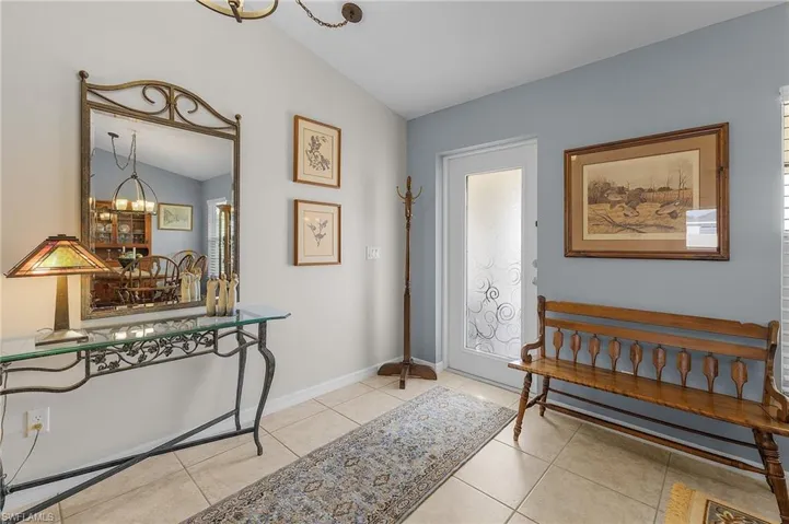 Foyer with a notable chandelier, light tile patterned floors, and vaulted ceiling
