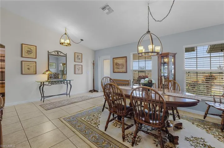 Dining space with vaulted ceiling, an inviting chandelier, and light tile patterned flooring