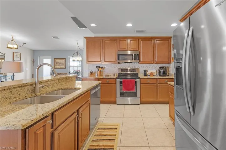 Kitchen with sink, an inviting chandelier, hanging light fixtures, and appliances with stainless steel finishes
